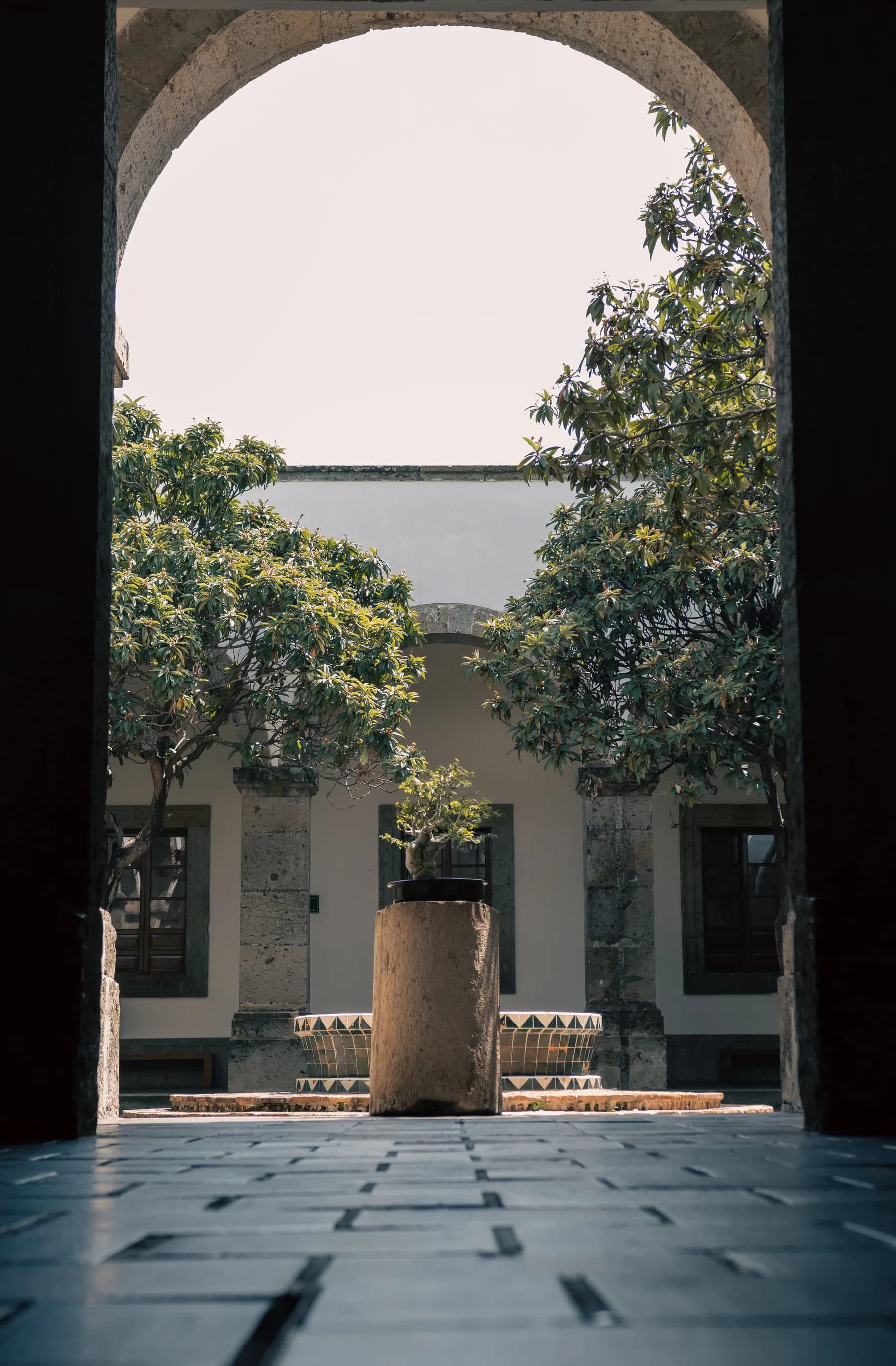 Patio tapatío con arcos de cantera y árboles