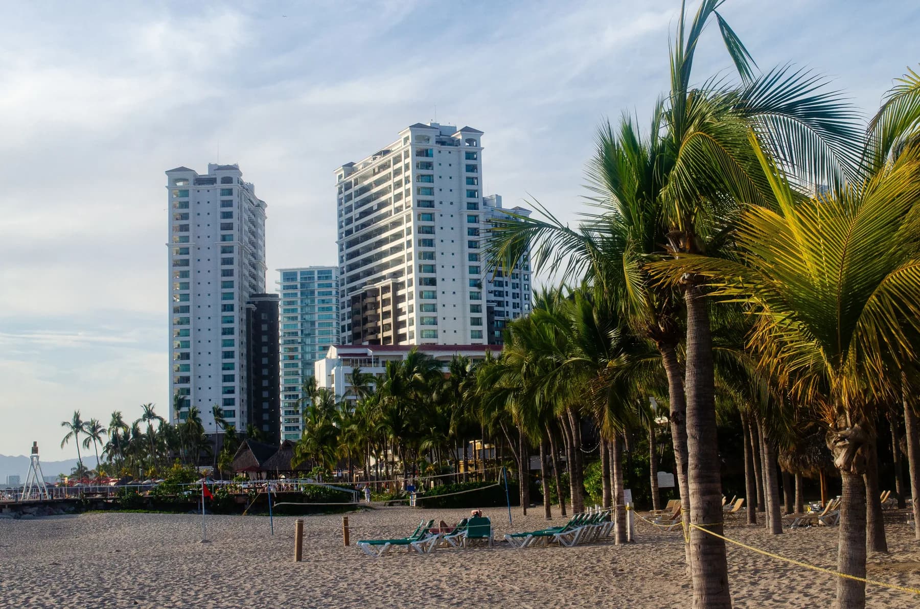 Torres de condominios frente a una playa de palmeras en la costa del Pacífico